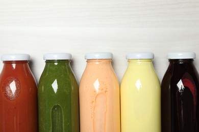 Photo of Superfood. Bottles with healthy drinks on light wooden table, flat lay. Space for text