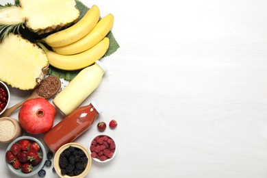 Photo of Superfood. Bottles with tasty smoothies and ingredients on light wooden table, flat lay. Space for text