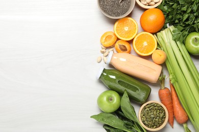 Photo of Superfood. Bottles with tasty smoothies and ingredients on light wooden table, flat lay. Space for text