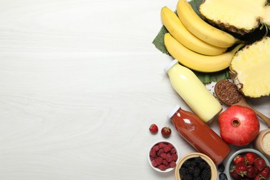 Photo of Superfood. Bottles with tasty smoothies and ingredients on light wooden table, flat lay. Space for text