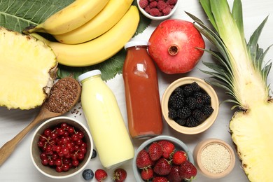 Photo of Superfood. Bottles with tasty smoothies and ingredients on light wooden table, flat lay