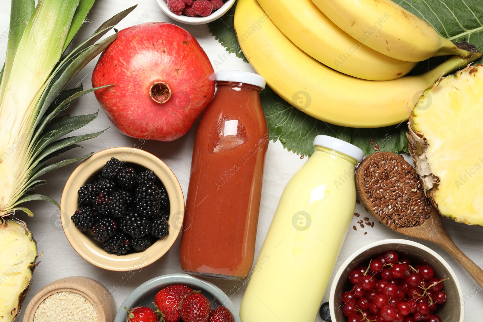Superfood. Bottles with tasty smoothies and ingredients on light wooden table, flat lay Photo of Superfood. Bottles with tasty smoothies and ingredients on light wooden table, flat lay