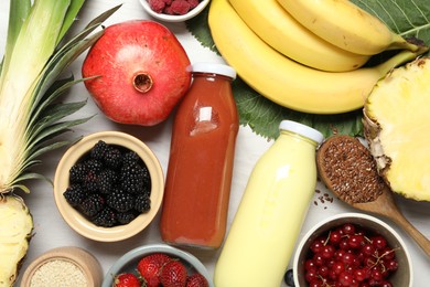 Photo of Superfood. Bottles with tasty smoothies and ingredients on light wooden table, flat lay