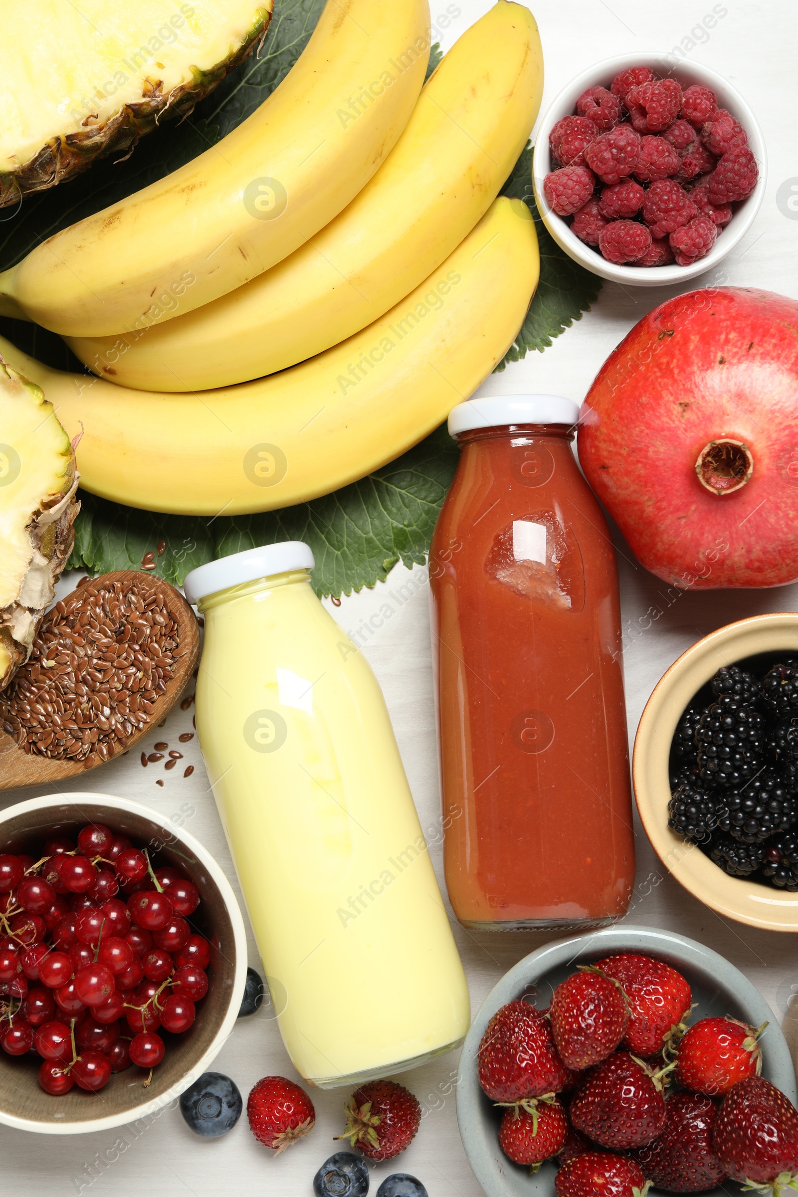 Superfood. Bottles with tasty smoothies and ingredients on light wooden table, flat lay Photo of Superfood. Bottles with tasty smoothies and ingredients on light wooden table, flat lay
