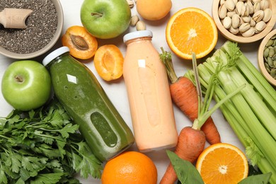 Photo of Superfood. Bottles with tasty smoothies and ingredients on light wooden table, flat lay