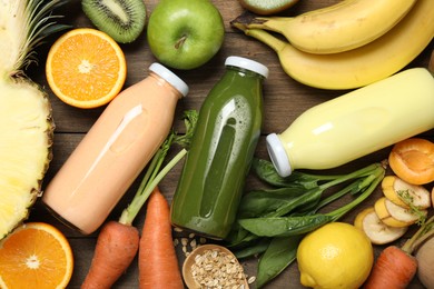 Photo of Superfood. Tasty smoothies in bottles and ingredients on wooden table, flat lay