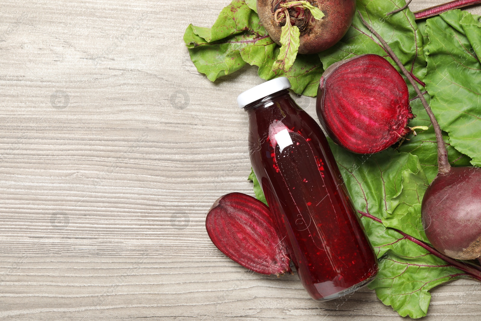 Superfood. Tasty juice in bottle and beetroots on light wooden table, flat lay. Space for text Photo of Superfood. Tasty juice in bottle and beetroots on light wooden table, flat lay. Space for text