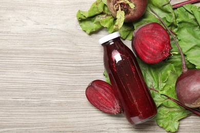 Photo of Superfood. Tasty juice in bottle and beetroots on light wooden table, flat lay. Space for text