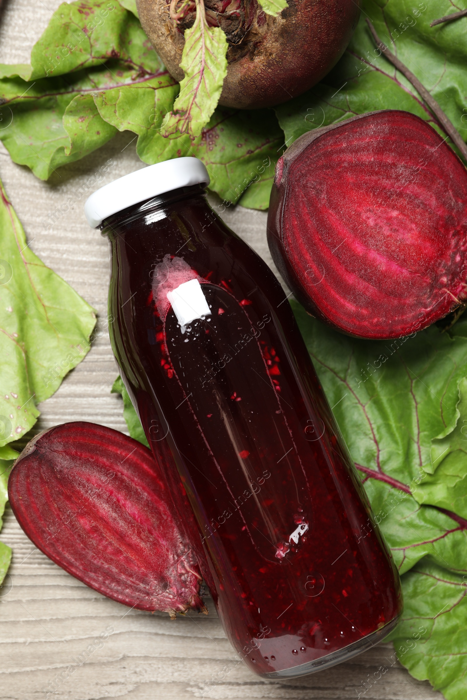 Superfood. Tasty juice in bottle and beetroots on light wooden table, flat lay Photo of Superfood. Tasty juice in bottle and beetroots on light wooden table, flat lay