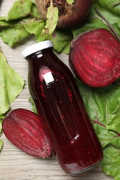 Photo of Superfood. Tasty juice in bottle and beetroots on light wooden table, flat lay