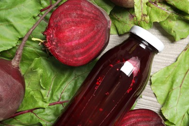 Photo of Superfood. Tasty juice in bottle and beetroots on light wooden table, flat lay