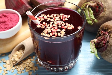 Photo of Superfood. Tasty juice with oats in glass and beetroots on light blue wooden table, closeup