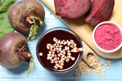 Photo of Superfood. Tasty juice with oats in glass, powder and beetroots on light blue wooden table, flat lay