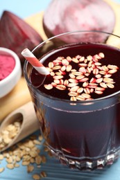 Photo of Superfood. Tasty juice with oats in glass and beetroots on light blue wooden table, closeup