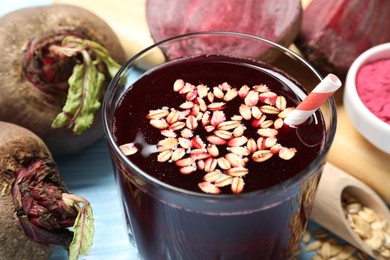 Photo of Superfood. Tasty juice with oats in glass and beetroots on light blue table, closeup