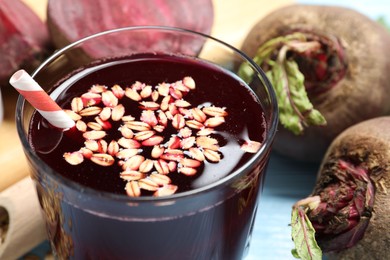 Photo of Superfood. Tasty juice with oats in glass and beetroots on light blue table, closeup