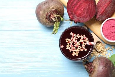 Photo of Superfood. Tasty juice with oats in glass, powder and beetroots on light blue wooden table, flat lay. Space for text