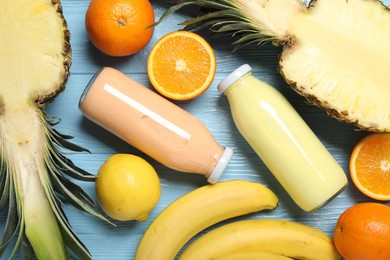 Photo of Superfood. Tasty smoothies in bottles and ingredients on light blue wooden table, flat lay