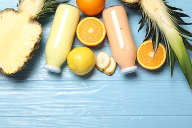 Photo of Superfood. Tasty smoothies in bottles and ingredients on light blue wooden table, flat lay. Space for text