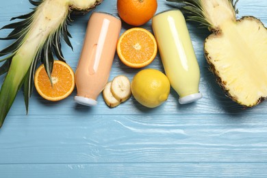 Photo of Superfood. Tasty smoothies in bottles and ingredients on light blue wooden table, flat lay. Space for text