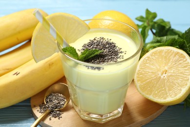 Photo of Superfood. Tasty smoothie with chia seeds in glass and ingredients on light blue wooden table, closeup