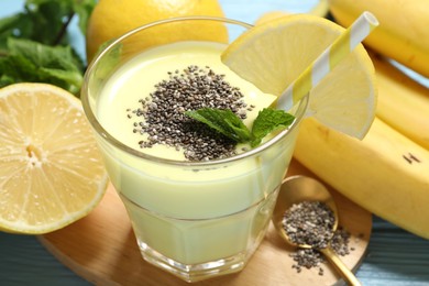 Photo of Superfood. Tasty smoothie with chia seeds in glass and ingredients on light blue wooden table, closeup