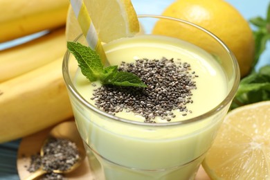 Photo of Superfood. Tasty smoothie with chia seeds in glass and ingredients on light blue wooden table, closeup