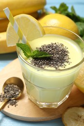 Photo of Superfood. Tasty smoothie with chia seeds in glass and ingredients on light blue wooden table, closeup