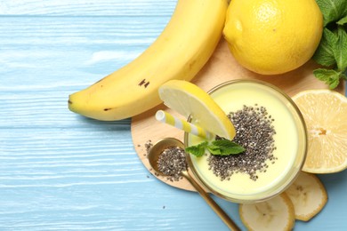 Photo of Superfood. Tasty smoothie with chia seeds in glass and ingredients on light blue wooden table, flat lay. Space for text