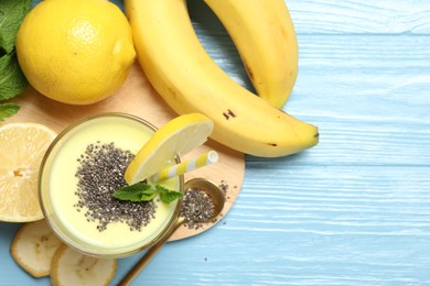 Photo of Superfood. Tasty smoothie with chia seeds in glass and ingredients on light blue wooden table, flat lay. Space for text
