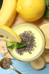 Photo of Superfood. Tasty smoothie with chia seeds in glass and ingredients on light blue wooden table, flat lay