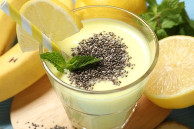 Photo of Superfood. Tasty smoothie with chia seeds in glass and ingredients on light blue table, closeup