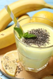 Photo of Superfood. Tasty smoothie with chia seeds in glass and ingredients on light blue table, closeup