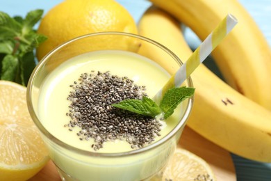 Photo of Superfood. Tasty smoothie with chia seeds in glass and ingredients on light blue table, closeup
