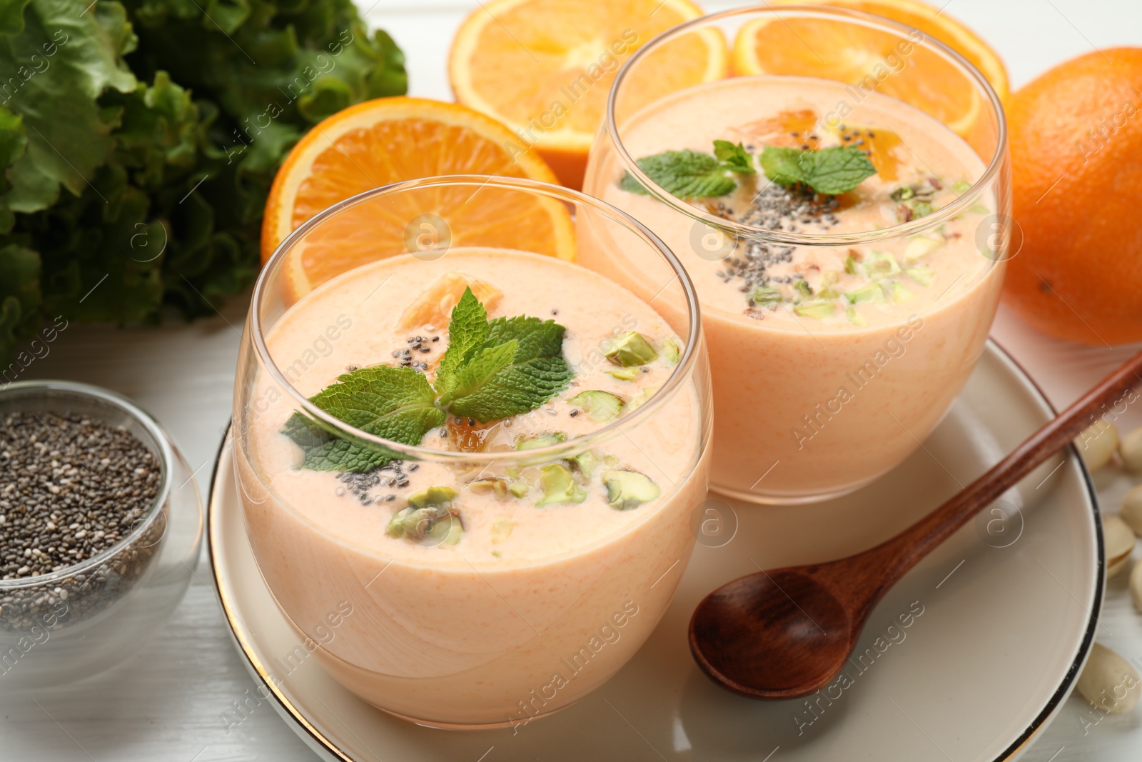 Superfood. Tasty smoothie with chia seeds, mint, pistachio and oranges on white wooden table, closeup Photo of Superfood. Tasty smoothie with chia seeds, mint, pistachio and oranges on white wooden table, closeup