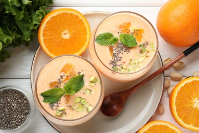 Photo of Superfood. Tasty smoothie with chia seeds, mint, pistachio and oranges on white wooden table, flat lay