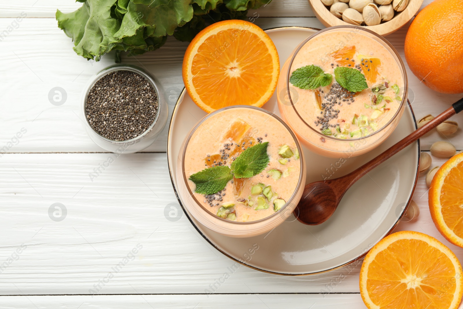 Superfood. Tasty smoothie with chia seeds, mint, pistachio and oranges on white wooden table, flat lay Photo of Superfood. Tasty smoothie with chia seeds, mint, pistachio and oranges on white wooden table, flat lay