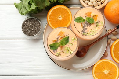 Photo of Superfood. Tasty smoothie with chia seeds, mint, pistachio and oranges on white wooden table, flat lay