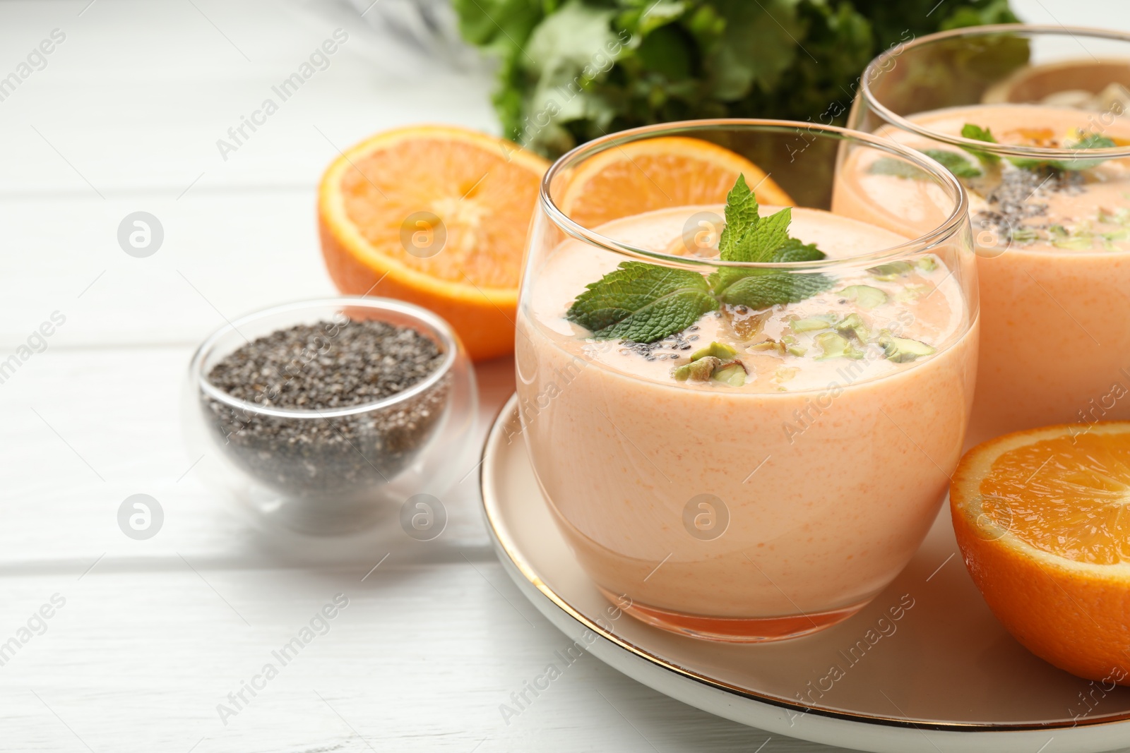 Superfood. Tasty smoothie with chia seeds, mint, pistachio and oranges on white wooden table, closeup Photo of Superfood. Tasty smoothie with chia seeds, mint, pistachio and oranges on white wooden table, closeup