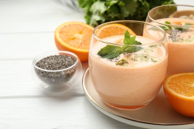 Photo of Superfood. Tasty smoothie with chia seeds, mint, pistachio and oranges on white wooden table, closeup