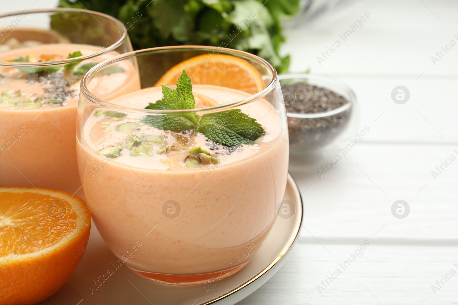 Superfood. Tasty smoothie with chia seeds, mint, pistachio and oranges on white wooden table, closeup Photo of Superfood. Tasty smoothie with chia seeds, mint, pistachio and oranges on white wooden table, closeup
