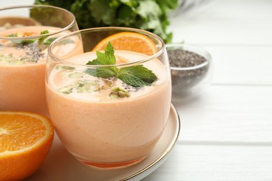 Photo of Superfood. Tasty smoothie with chia seeds, mint, pistachio and oranges on white wooden table, closeup