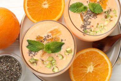 Photo of Superfood. Tasty smoothie with chia seeds, mint, pistachio and oranges on white wooden table, flat lay