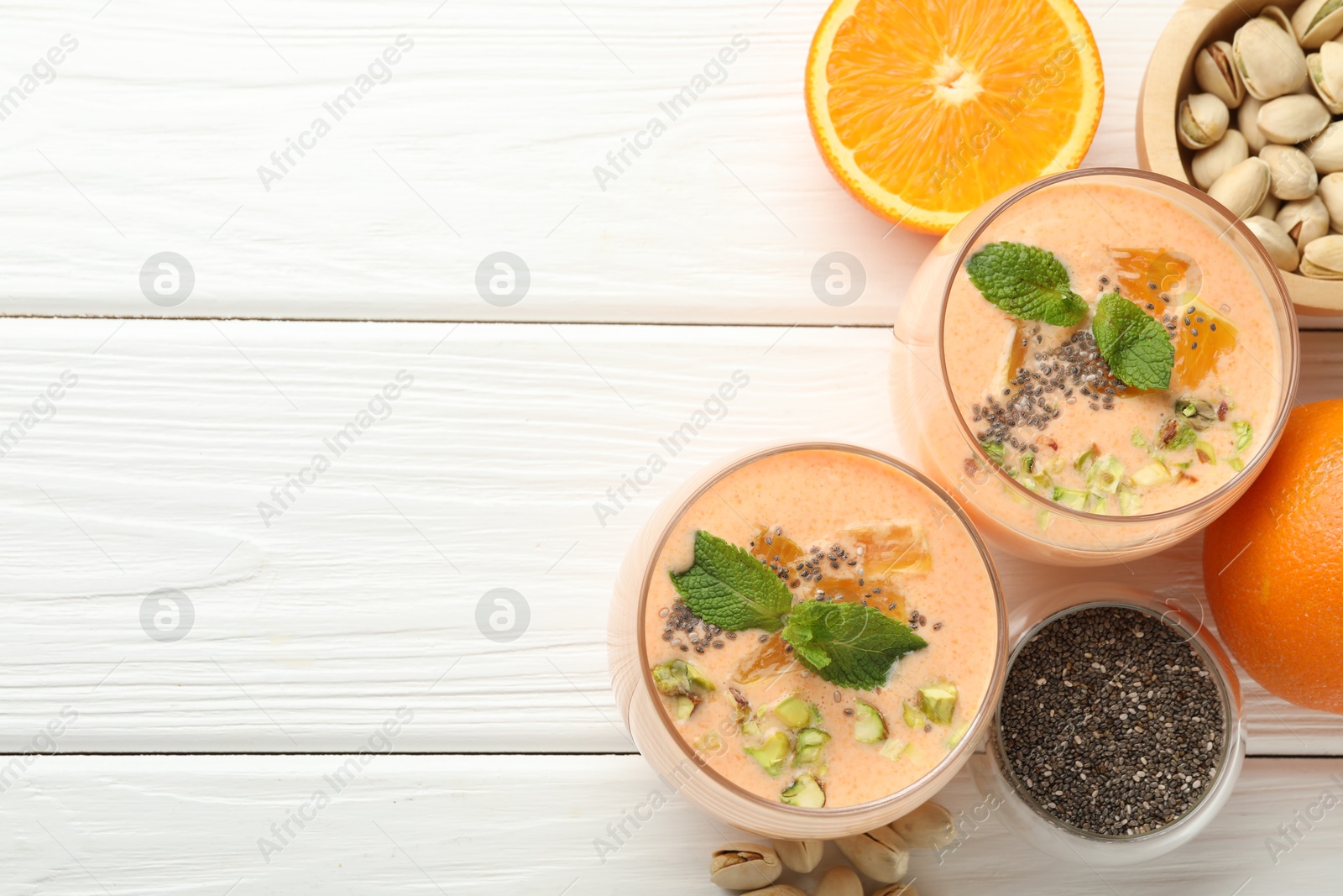 Superfood. Tasty smoothie with chia seeds, mint, pistachio and oranges on white wooden table, flat lay. Space for text Photo of Superfood. Tasty smoothie with chia seeds, mint, pistachio and oranges on white wooden table, flat lay. Space for text