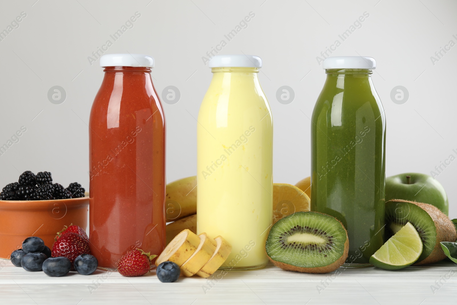 Superfood. Bottles with tasty smoothies and ingredients on white wooden table, closeup Photo of Superfood. Bottles with tasty smoothies and ingredients on white wooden table, closeup