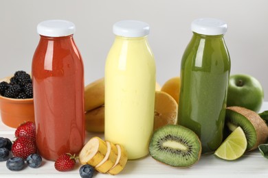 Photo of Superfood. Bottles with tasty smoothies and ingredients on white wooden table, closeup