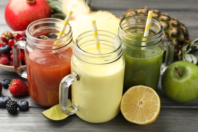 Photo of Superfood. Tasty smoothies in mason jars and ingredients on grey wooden table, closeup