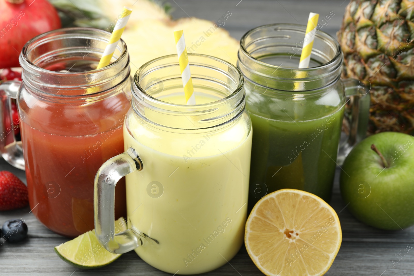 Superfood. Tasty smoothies in mason jars and ingredients on grey wooden table, closeup Photo of Superfood. Tasty smoothies in mason jars and ingredients on grey wooden table, closeup