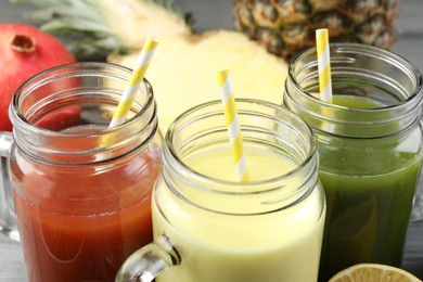Photo of Superfood. Tasty smoothies in mason jars and ingredients on grey table, closeup