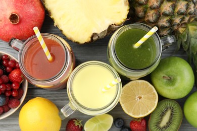 Photo of Superfood. Tasty smoothies in mason jars and ingredients on grey wooden table, flat lay